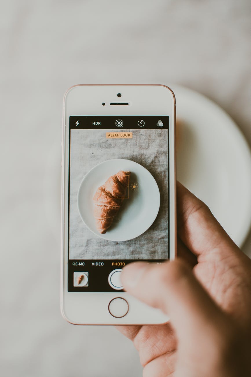 person taking photo of croissant bread